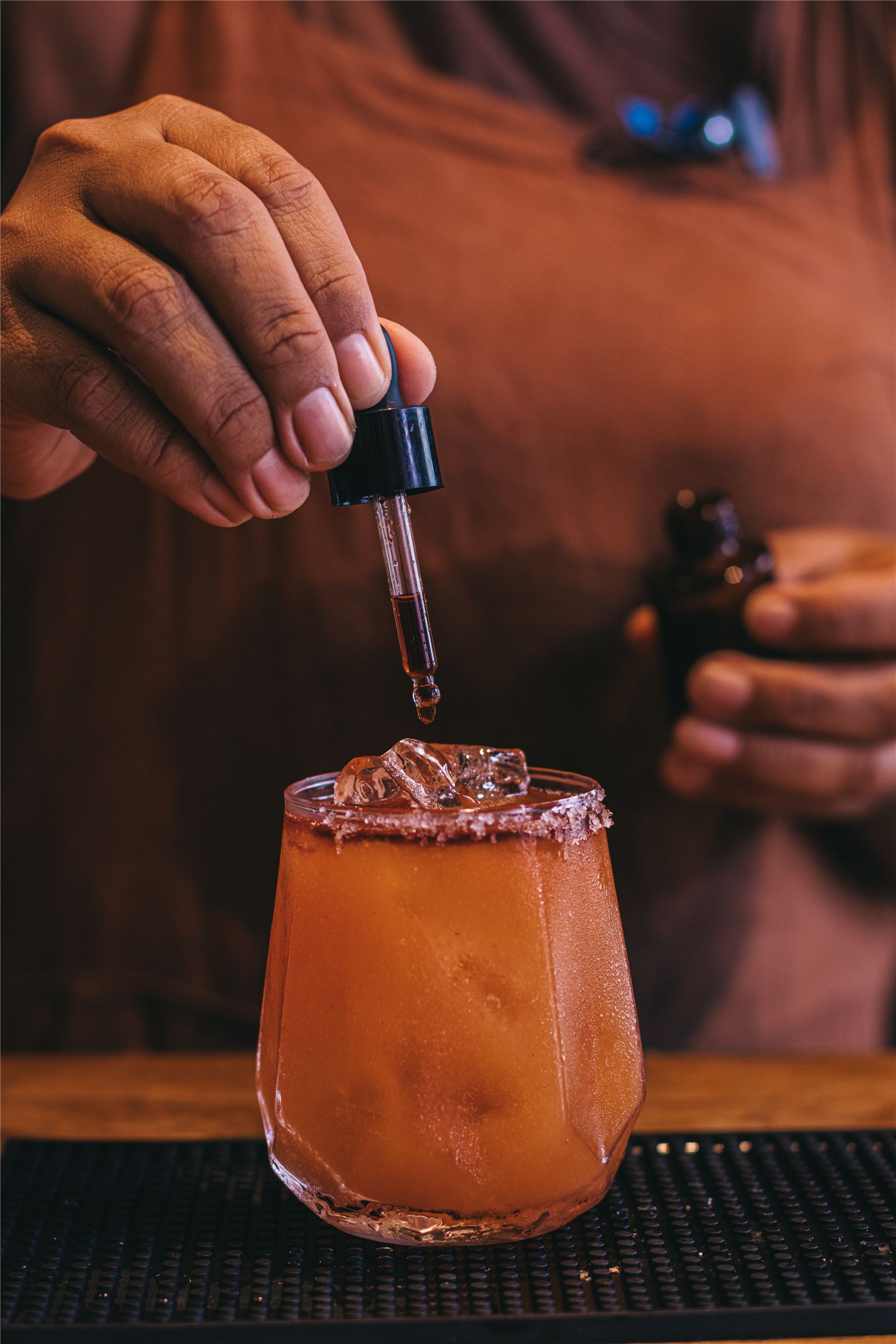 Bartender finalizando drink de cachaça com bitters no balcão do Gracinha